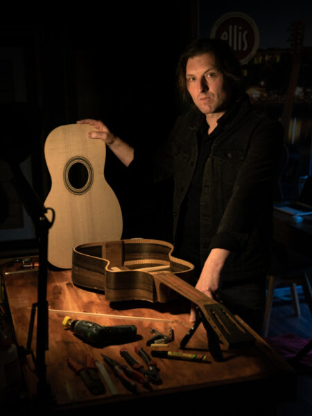 Andrew Ellis in the Ellis Guitars workshop, surrounded by tools and finely crafted guitars.